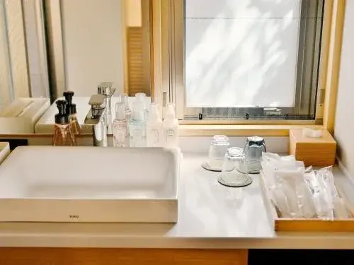 Vanity counter laid with skincare amenities beside a light-filled wooden window