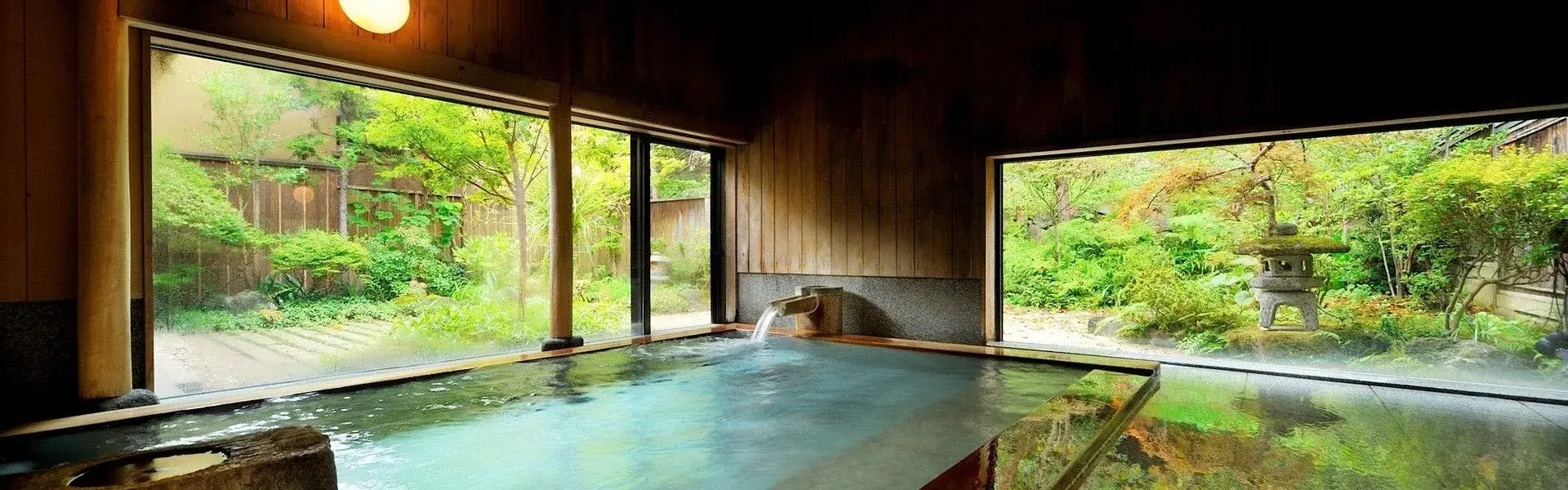Meigetsuso's indoor onsen bath with stone lantern and garden framed by wide timber windows