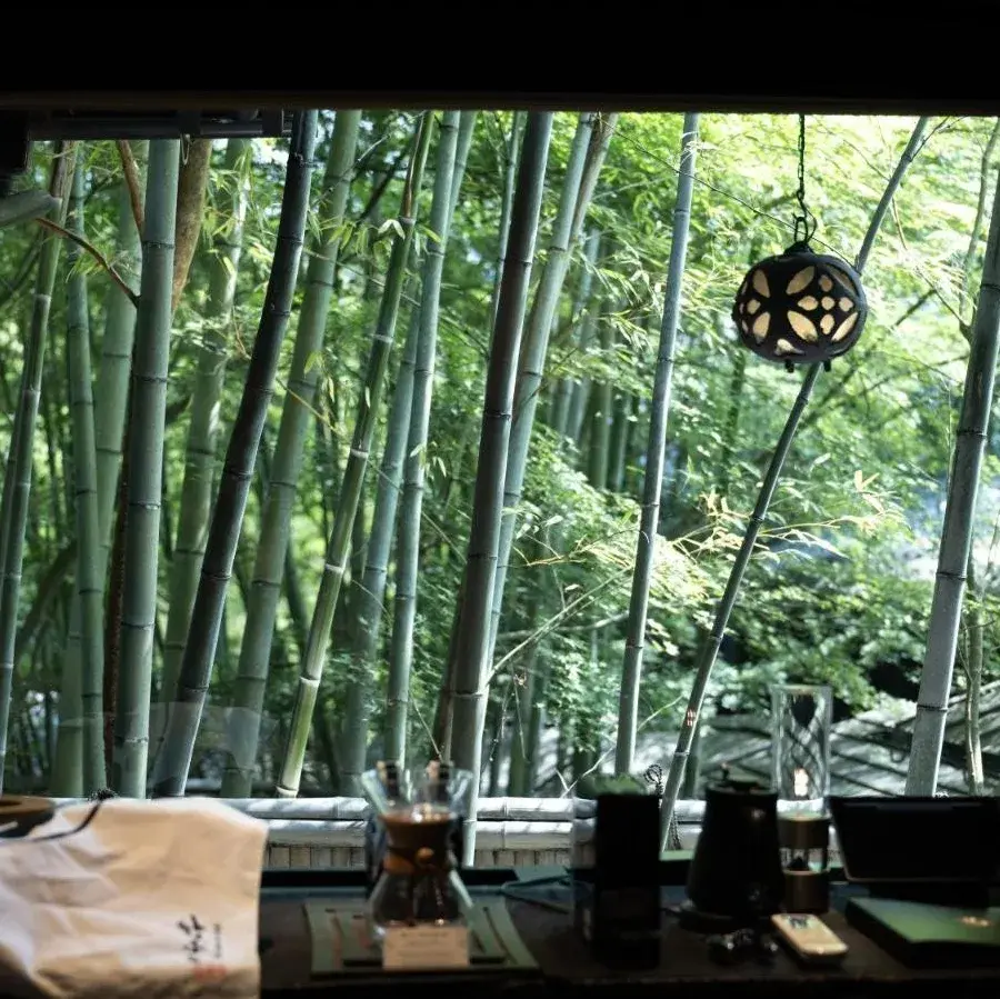 Dining table overlooking Takefue's dense bamboo grove through floor-to-ceiling windows