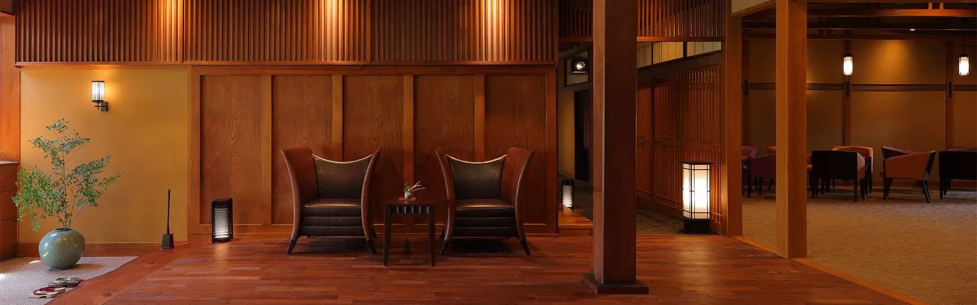 Warm wood lobby with leather armchairs and shoji lanterns at Fuefukigawa