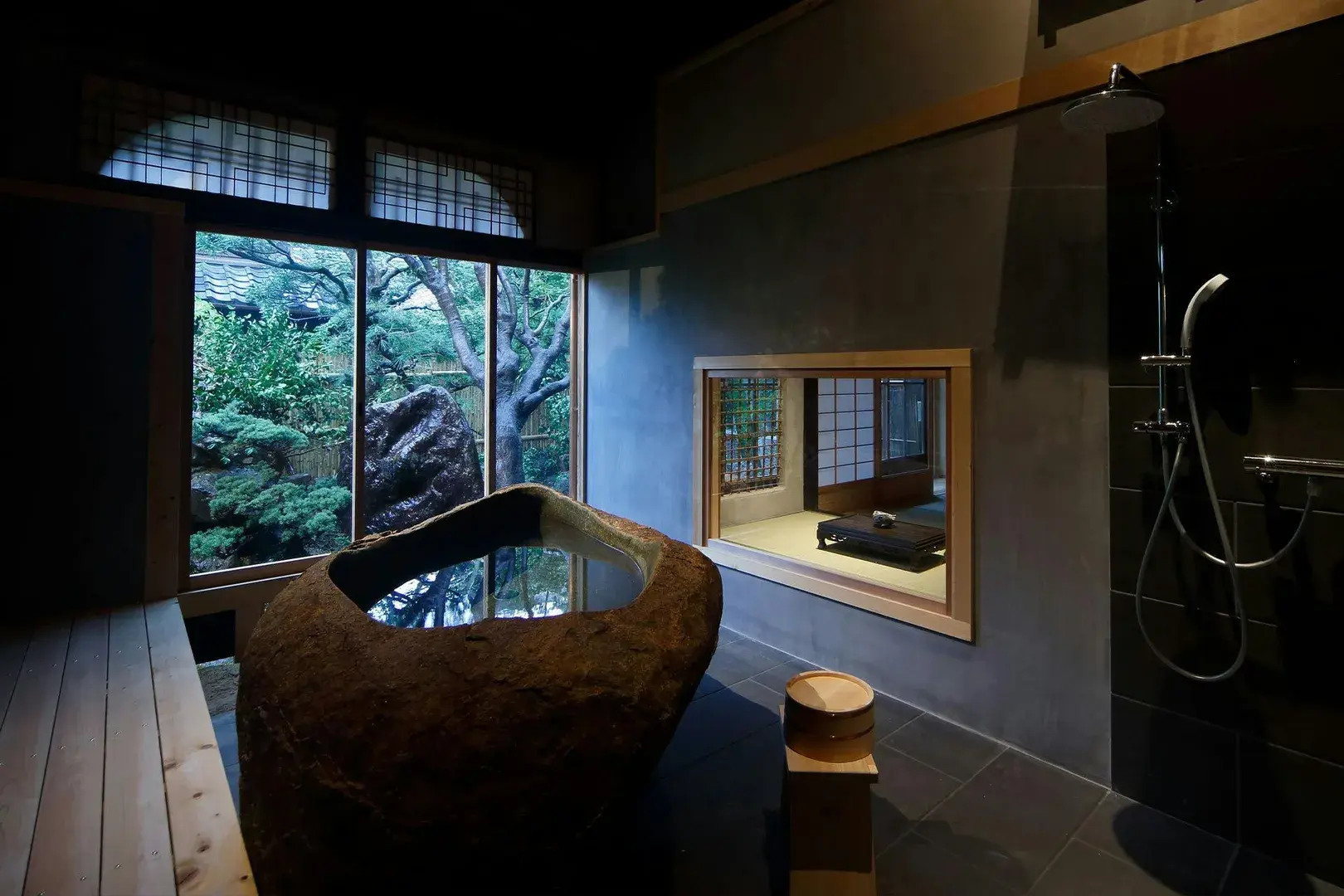 Hatago Wakatsu's boulder-carved stone bath with garden view through shoji windows