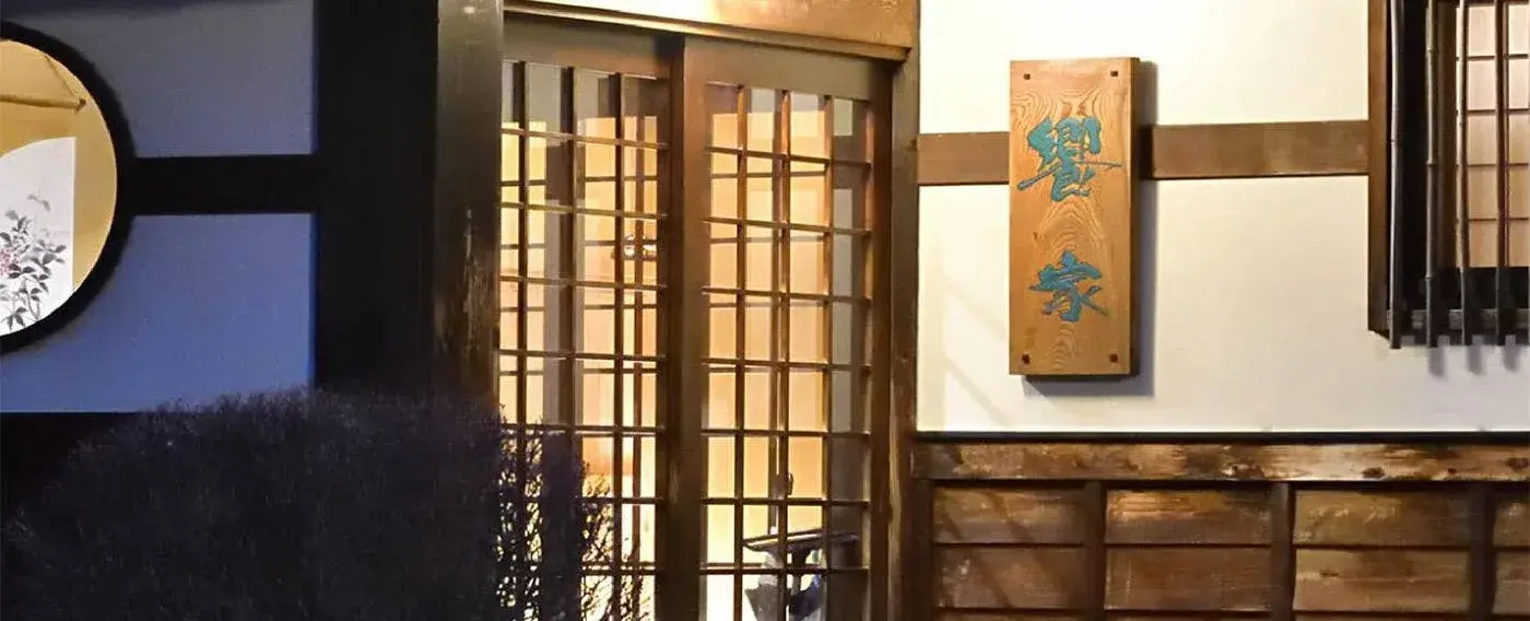 Kyoya's entrance at dusk, carved wooden nameplate beside lattice shoji doors
