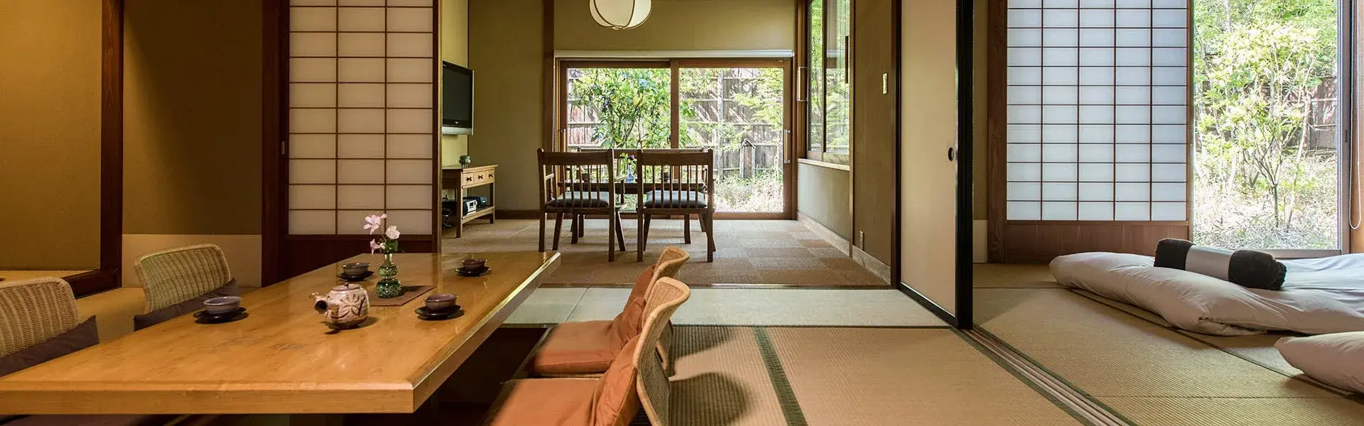 Tatami room with low dining table and shoji screens opening to a private garden at Sakura-yu Sanshuyu