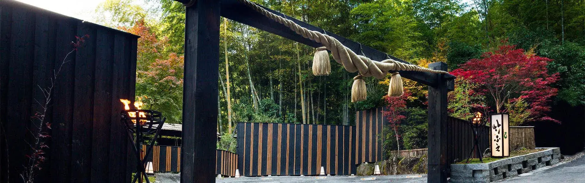 Takefue's rope-hung entrance gate framed by bamboo grove and autumn maple