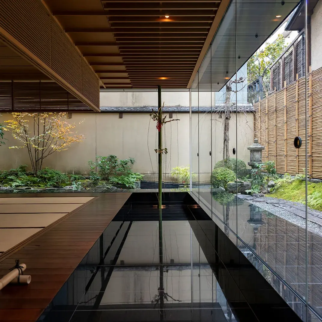 Indoor stone bath at Hiiragiya, glass walls framing a moss and maple courtyard