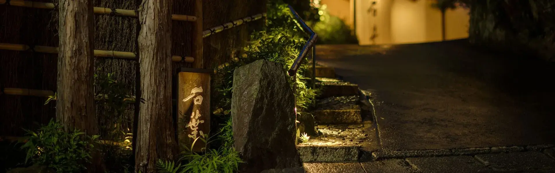 Sekiyo's stone entrance sign lit at night along a Yugawara garden path