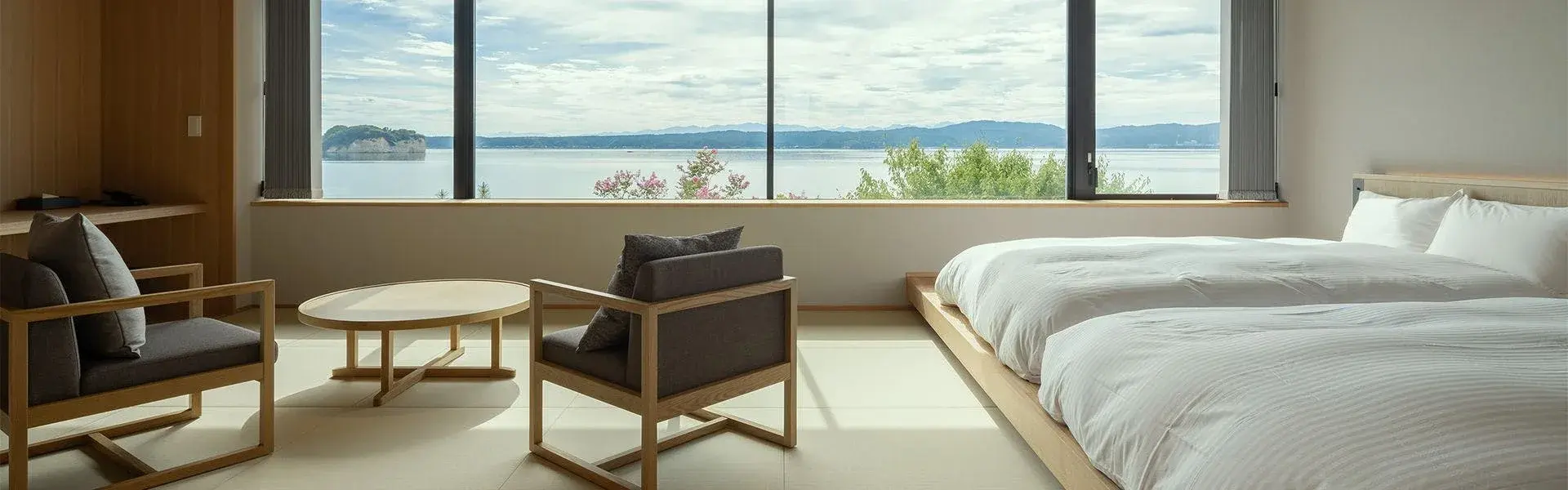 Minimalist tatami room with platform beds and Nanao Bay beyond the window