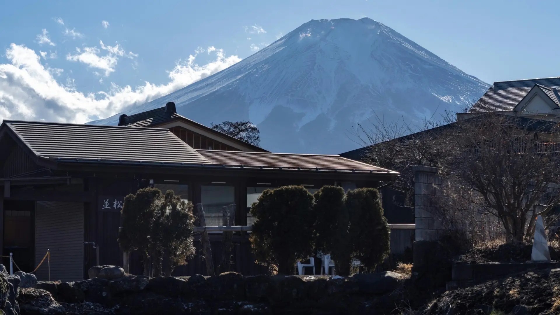 Snow-capped Mount Fuji rising dramatically behind low-rise buildings and rooftops in clear winter light